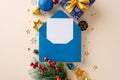 This top-view image features envelope, gift box, blue and gold baubles, confetti, wintry elements on beige background Royalty Free Stock Photo
