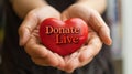 Embrace Life through Donation. A close-up of hands cradling a glossy red heart with the message & x22;Donate Life Save Lives Royalty Free Stock Photo