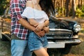 embrace.Love and affection between a young couple at the park, near the old car. a guy in a plaid plane and jeans, a girl in short Royalty Free Stock Photo
