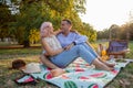 Embraced couple sitting on blanket intent on vegan picnic looks into each other's eyes with love