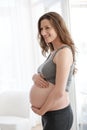 Embracing her maternal instincts. a young pregnant woman standing in her home.