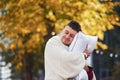 Embracing the pillow. Young man in pajama is outdoors on the street. Feels sleepy