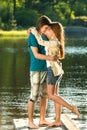 Embracing teens standing barefoot on pier