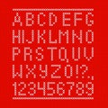 Embroided by cross stitch english alphabet with numbers and symbols on red cloth texture.