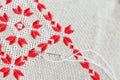 Embroidered fragment on flax by red and white cotton threads. Macro embroidery texture flat stitch.
