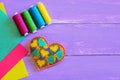 Embroidered heart for Valentines Day. Felt heart ornament, thread set, colorful felt sheets on a purple wooden background