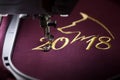 Embroidery with embroidery machine of dog silhouette and number 2018 in gold on claret fabric Royalty Free Stock Photo