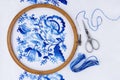 Embroidery hoop with fabric, sewing needle and thread, top view. Blue floral ornament on a white background Royalty Free Stock Photo