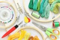 Embroidery hoop and multicolored accessories on white linen canvas with spools of thread, needle and scissors Royalty Free Stock Photo