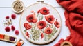 Embroidery of poppy flowers in round hoop on white wooden table. Cross stitch illustration showing love to needlework and interest