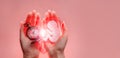 Embryo silhouette from paper and clock in woman hands with broken heart. Hands on the left side. Pink back ground with copy space