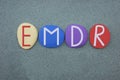 EMDR, Eye Movement Desensitization and Reprocessing, creative text composed with multi colored stone letters over green sand Royalty Free Stock Photo