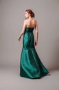 Emerald ball gown. Young lady in long green evening dress. Ginger woman posing in studio. Royalty Free Stock Photo