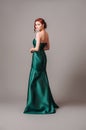 Emerald ball gown. Young lady in long green evening dress. Ginger woman posing in studio Royalty Free Stock Photo