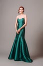 Emerald ball gown. Young lady in long green evening dress. Ginger woman posing in studio Royalty Free Stock Photo