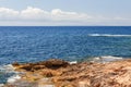 Emerald blue Mediterranean warm water gently caresses orange rocky cliff, Ibiza, Balearic Islands, Spain