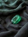 Emerald gemstone on dark fabric background