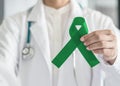 Emerald green or jade color ribbon in doctor`s hand symbolic for Liver Cancer and Hepatitis B disease awareness concept Royalty Free Stock Photo
