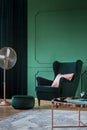 Emerald green velvet armchair with pastel pillow in trendy living room interior with copper accents Royalty Free Stock Photo