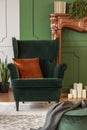 Green wing back chair with orange pillow in luxury living room interior