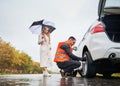 Emergency auto mechanic changing flat tire on woman car. Royalty Free Stock Photo