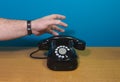 Emergency call. Hand reaches for the old phone. Old telephone set on a wooden table. Copy space Royalty Free Stock Photo