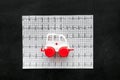 Emergency care concept. Ambulance vehicle toy near cardiogram on black background top view