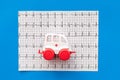 Emergency care concept. Ambulance vehicle toy near cardiogram on blue background top view