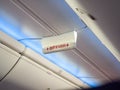 Emergency exit sign in airplane. Word red color in Thai language mean exit way on sign hanging on ceiling on the airplane
