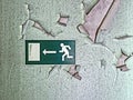 Emergency exit sign in old building on wall with peeling paint Royalty Free Stock Photo