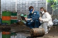 emergency pollution factory concept. engineers wearing mechanic jumpsuits and ppe and gas masks inspect oil on the factory floor