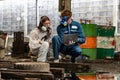 emergency pollution factory concept. engineers wearing mechanic jumpsuits and ppe and gas masks inspect oil on the factory floor