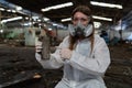 emergency pollution factory concept. Female chemist wearing PPE and gas mask inspecting oil on factory floor Royalty Free Stock Photo