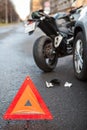 Emergency road triangle sign is on asphalt, road accident with car and motorcycle