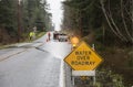 Emergency workers road crew placing warning signs on flooded highway. Hazards after a rain storm. Royalty Free Stock Photo