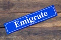 Emigrate street sign on wooden background Royalty Free Stock Photo