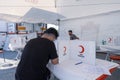a male person volunteer signing approval document for blood donation for Turkish Red Crescent Turk Kizilay under a portable tent