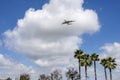 An Emirates airlines plane flying in the sky with lush green palm trees, blue sky and clouds in Inglewood California Royalty Free Stock Photo