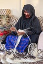 Emirati woman is weaving traditional basket from palm leaves