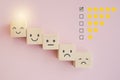 Emoticon face on wooden block with light over smiling , check box and rating star for customer experience, satisfaction survey, e- Royalty Free Stock Photo