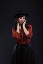 Emotion brunette female model posing in black hat with red bright lipstick on black background. Art fashion portrait. Royalty Free Stock Photo