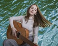 Emotion concept. Portrait of a young girl playing the guitar in front of the sea Royalty Free Stock Photo