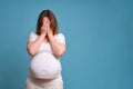 Emotion of crying pregnant woman, studio shot on blue background