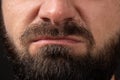 emotion of disgust, hatred close-up on face and lips of young unrecognizable man with black beard and mustache, concept