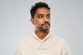 Indian man in knitted sweater over gray background