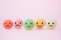 Emotion face on sweet macaron, , focus of happy green and defocus others, on sweet pink  background, customer review, feedback, Royalty Free Stock Photo