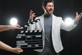 Emotional actor performing while second assistant camera holding clapperboard on black background, closeup