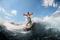 Emotional adult guy actively ride on the waves on surfboard against blue sky