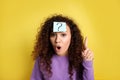 Emotional African-American woman with question mark sticker on forehead against background