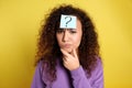 Emotional African-American woman with question mark sticker on forehead against background